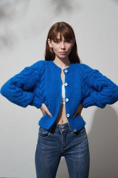 a woman in jeans and a blue sweater is posing for the camera with her hands on her hips