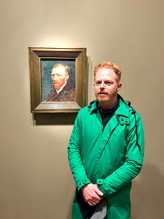 a man is standing in front of a painting and looking at the camera with his hands on his hips