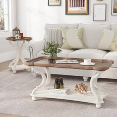 a living room filled with white furniture and pictures on the wall above it's coffee table