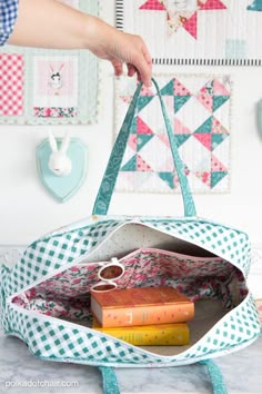 a person is holding a bag with books in it and some scissors on the table