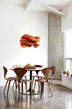 a dining room table with chairs and a lamp hanging from the ceiling in front of it