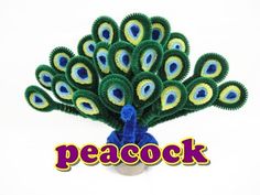 a peacock made out of yarn sitting on top of a white table next to the words peacock