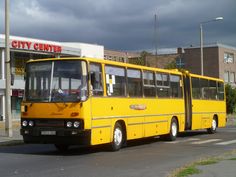 a yellow bus is parked in front of a city center store on the side of the road