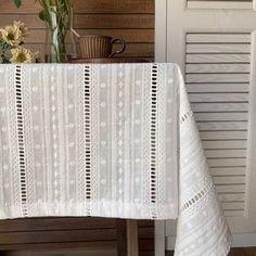 a white table cloth on top of a wooden table next to a vase with flowers