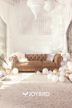 a living room filled with balloons and white furniture next to a wall covered in lights