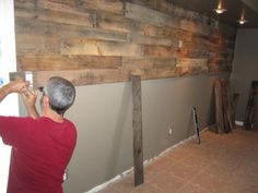 a man is painting a wall with wood planks