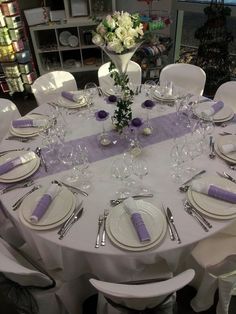 the table is set with purple and white place settings