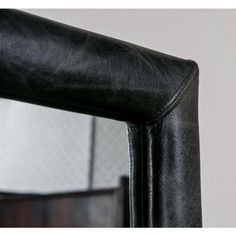 a close up of a black leather chair with a mirror on the wall behind it