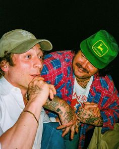 two men sitting next to each other with tattoos on their arms