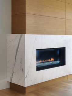 a modern fireplace with white marble surround and wood paneling