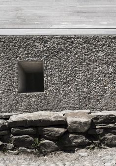 a stone wall with a small window in the center that reads ampiacion mect