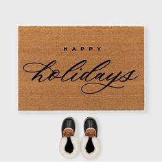 a pair of shoes sitting on top of a door mat with the words happy holidays