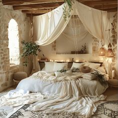 a large bed with white sheets and pillows in a room next to a stone wall