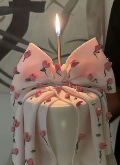 a white cake with pink flowers on it and a candle sticking out of the top