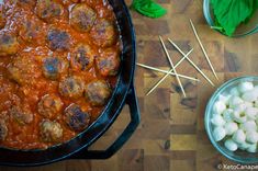 meatballs in tomato sauce with toothpicks next to bowl of garlic and basil