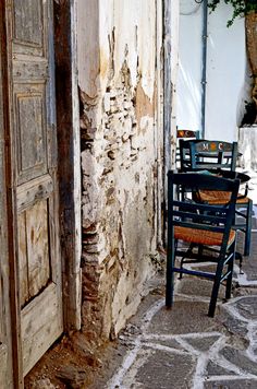 several chairs and tables are sitting in front of an old building with peeling paint on the walls