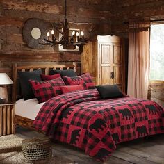 a bed with red and black plaid comforter in a rustic cabin bedroom, along with a chandelier