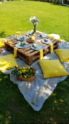 a picnic table set up in the grass with lemons, plates and flowers on it