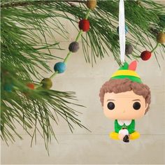 a christmas ornament hanging from a pine tree with a toy elf on it