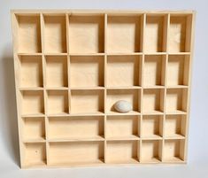 a wooden shelf with several compartments and a white ball on the bottom one is empty