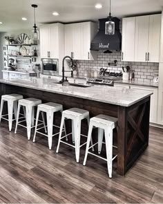 a kitchen island with four stools in front of it and an oven on the other side