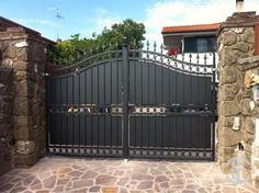 an iron gate in front of a stone house