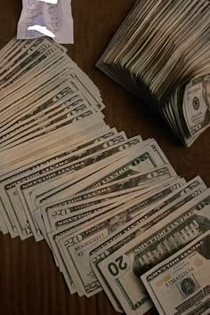 a pile of money sitting on top of a wooden table next to a stack of bills