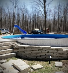 an empty swimming pool in the middle of a park with stone steps leading up to it