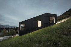 a black house sitting on top of a lush green hillside