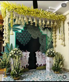 a room decorated in green and white with hanging decorations on the wall, potted plants and flowers