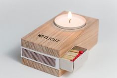 a matchbox with matches and a lit candle in it that says,'thichlott '