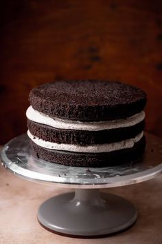 a chocolate cake with white frosting sitting on top of a glass plate