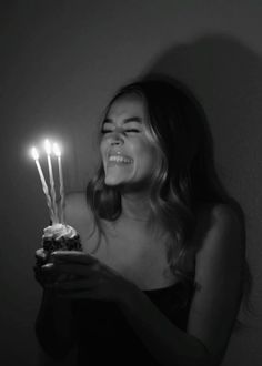 a woman holding a cupcake with candles in it