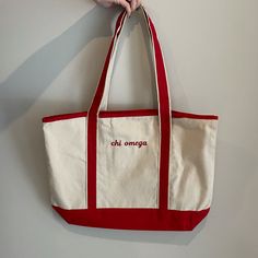 a hand holding a red and white bag with the word chi omga on it