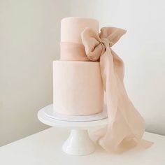 a three tiered pink cake with a bow on top