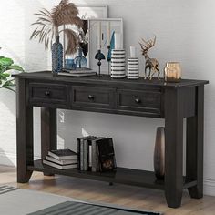 a black console table with two drawers and some pictures on the wall behind it in a room