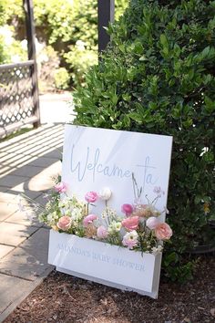 a welcome sign with pink and white flowers