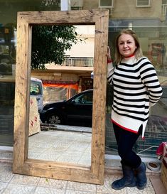 a woman standing in front of a large mirror on the side of a building with her reflection in it