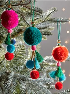 three ornaments hanging from a christmas tree with lights in the background