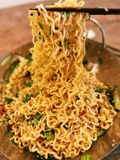 noodles being lifted from a bowl with chopsticks