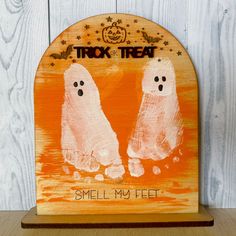 a wooden sign that says, smell my feet with two ghost hands painted on it