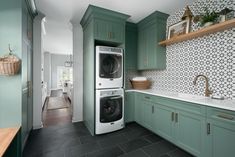 a washer and dryer in a kitchen with green cabinets, tile backsplash