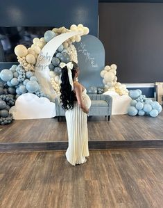 a woman is standing in front of a backdrop with balloons and an arch that reads happy birthday