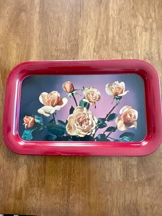 a red tray with flowers painted on the side and writing on the bottom, sitting on a wooden table