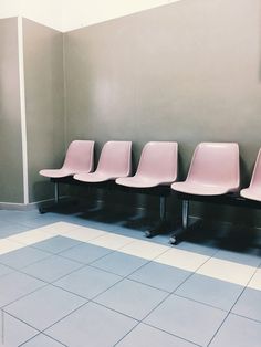 four pink chairs lined up against a wall in a waiting area by jodi lenski for stockstations