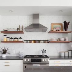 a stove top oven sitting inside of a kitchen next to wooden shelves filled with pots and pans