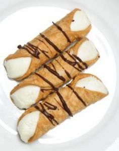 three croissants on a white plate with chocolate drizzled on them