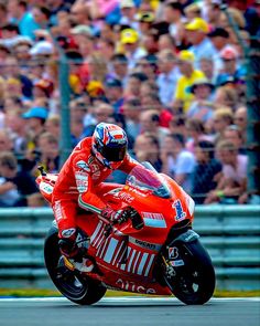 a man riding on the back of a red motorcycle in front of a large crowd