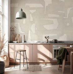 a modern kitchen with pink cabinets and white wallpaper on the walls, along with two stools