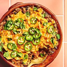 a wooden bowl filled with mexican food on top of a pink tile floor